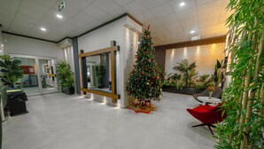 A modern lobby with a Christmas tree, seating area, and indoor plants. - City Life (Iskenderun)