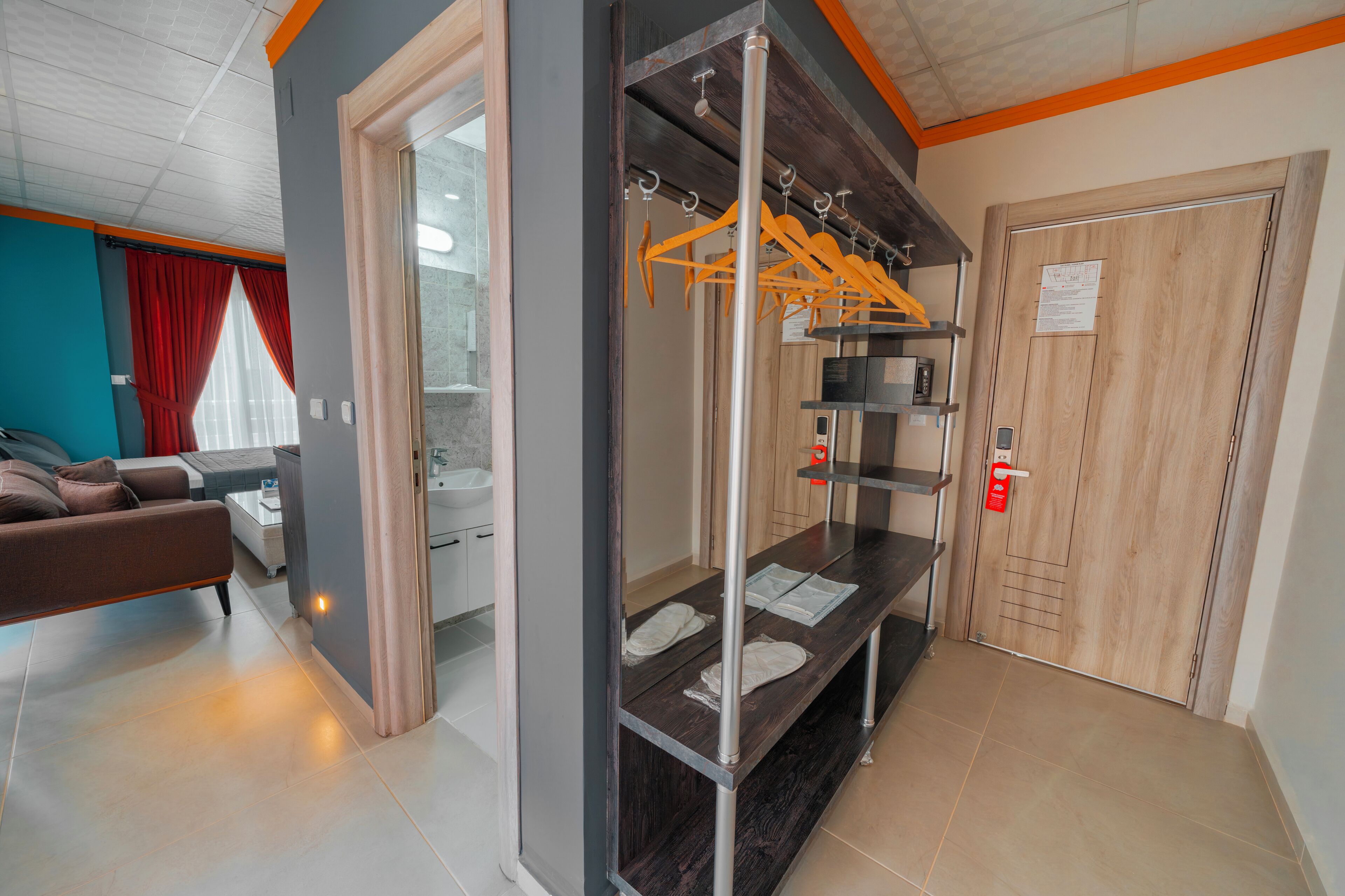 A hotel room with a bed, a bathroom, a wooden door, and a coat rack with hangers.
