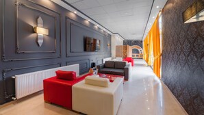 A modern hotel lobby with a long corridor, red and white seating areas, and patterned walls. - City Life (Iskenderun)