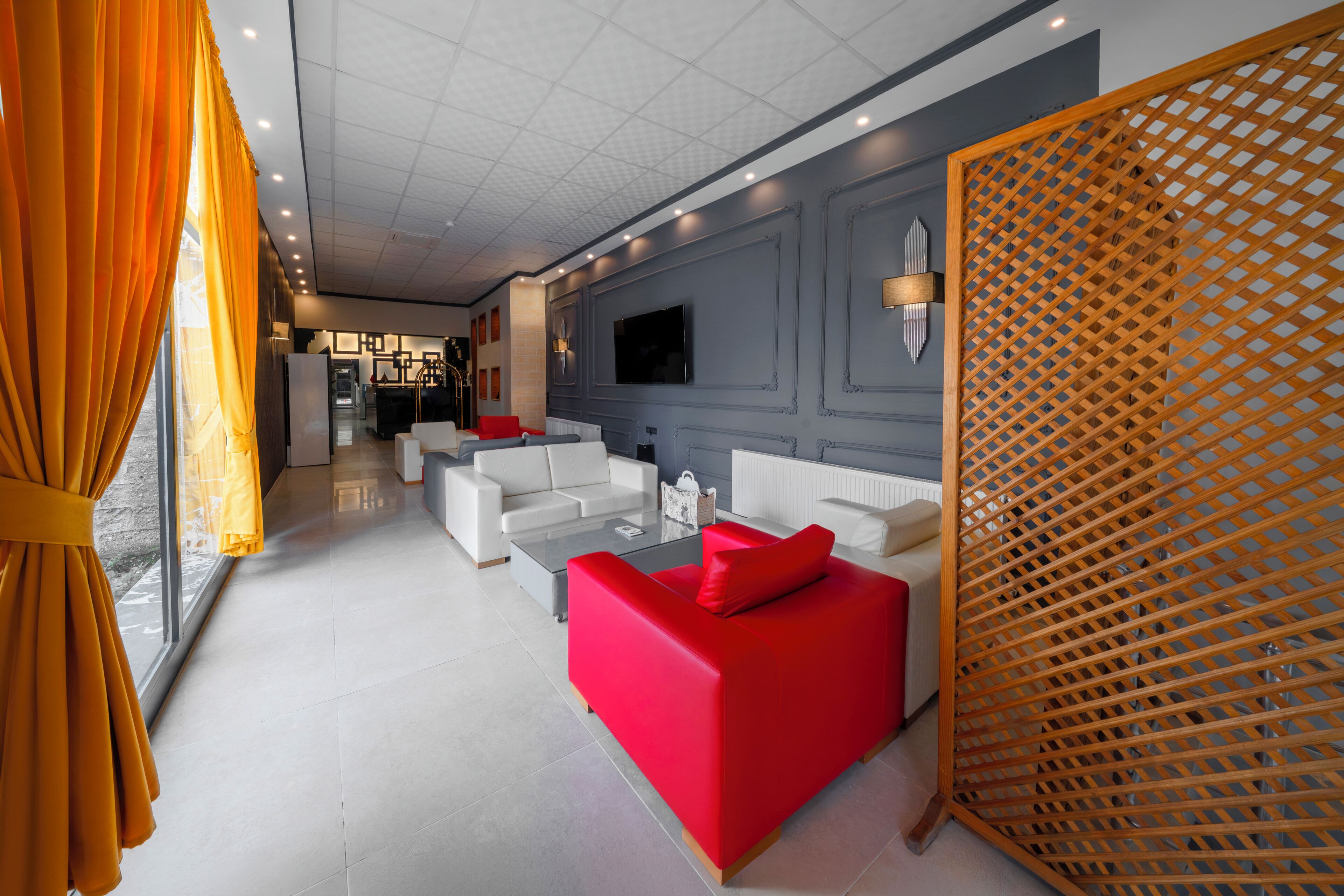 A modern living room with a red sofa, white armchairs, and a glass coffee table.