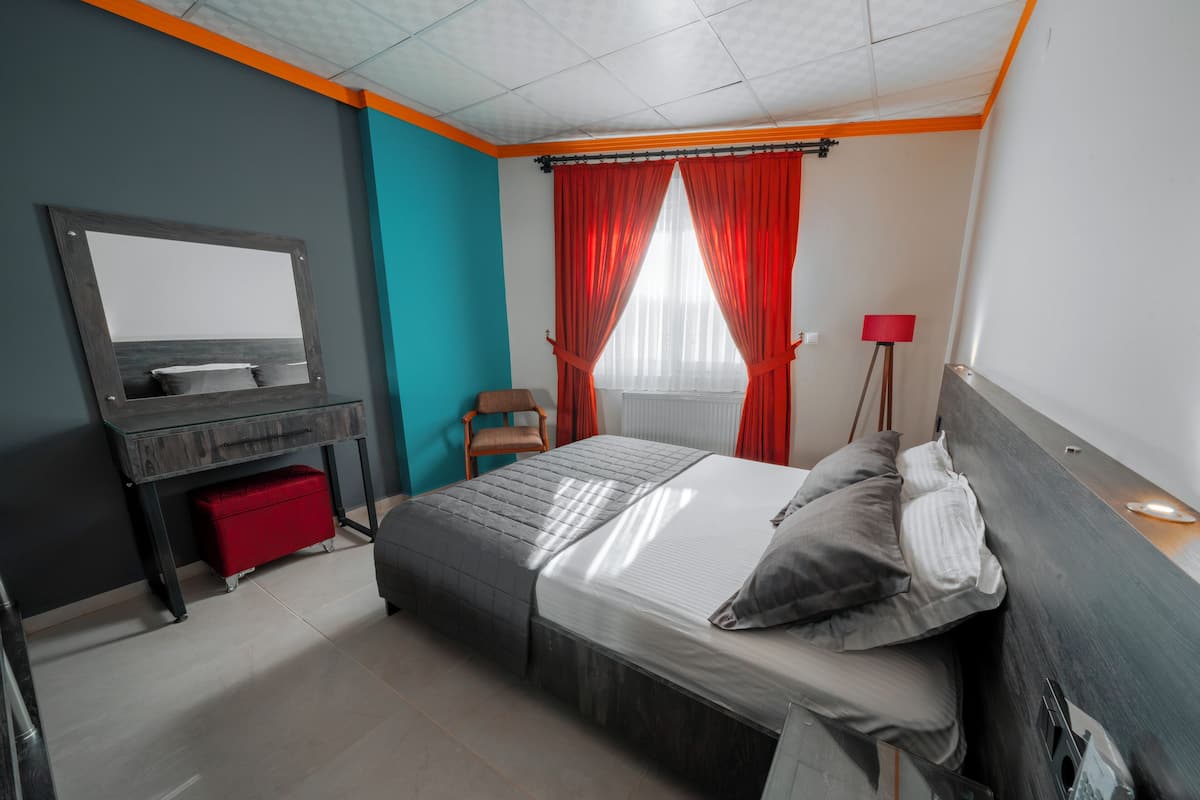 A modern bedroom with a bed, a desk, a chair, and a red lamp.