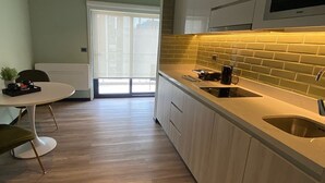 Una cocina moderna con un ventanal grande, un comedor con una mesa redonda y sillas, y un horno empotrado.