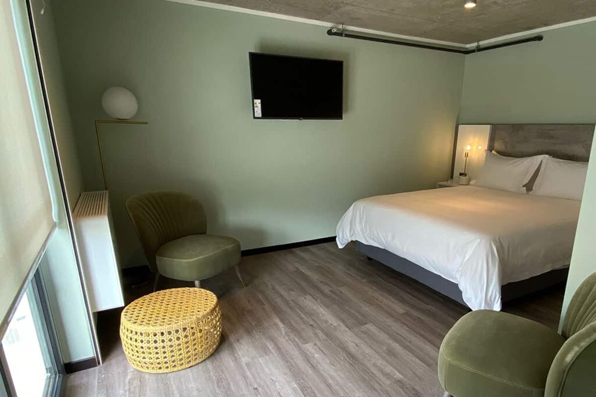 Una habitación de hotel con una cama, televisión, una silla y una pequeña mesa redonda.