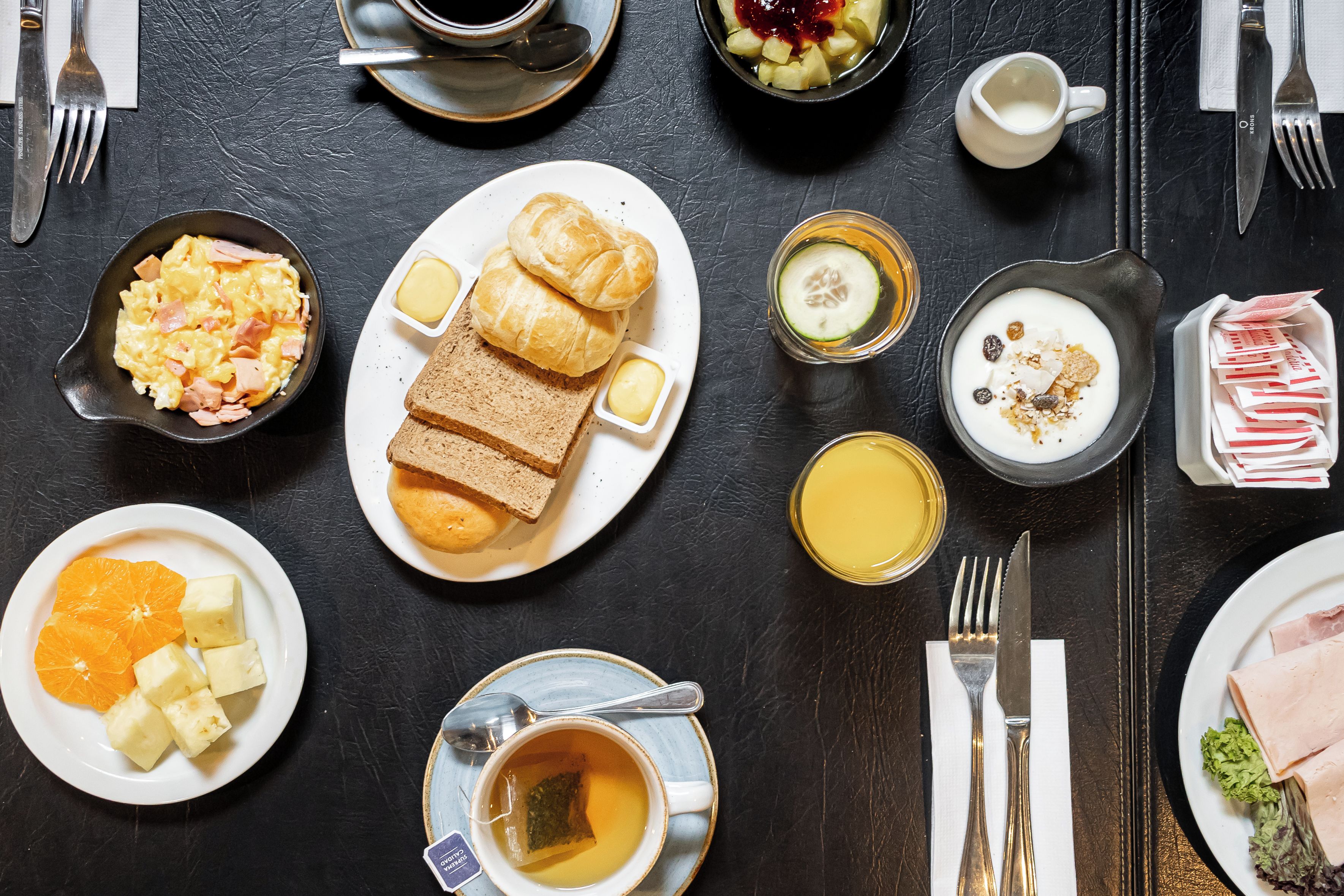 En morgenmadsopsætning med forskellige retter, herunder ristet brød, æg og frugt.