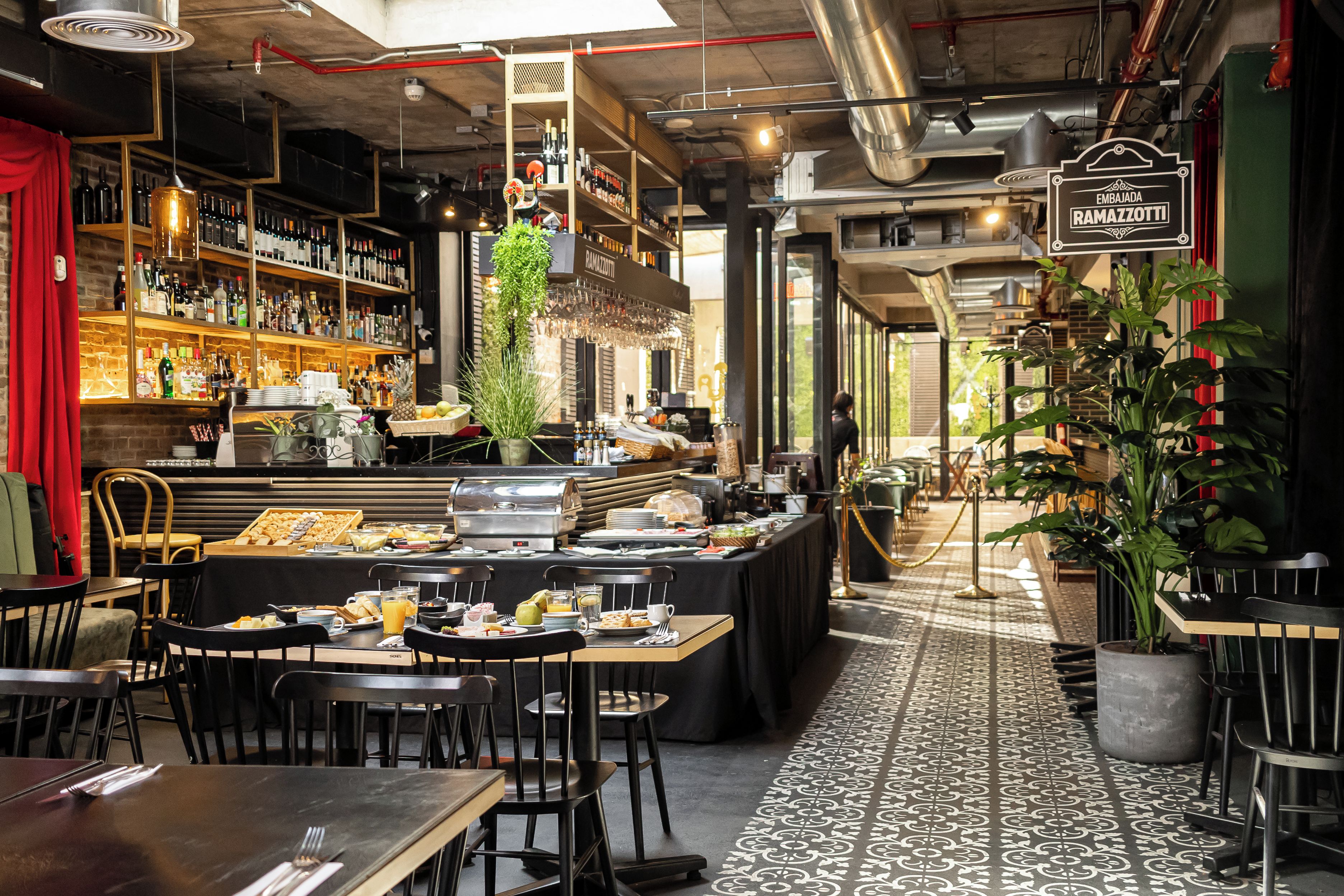 A restaurant with a bar area, dining tables, and a buffet.