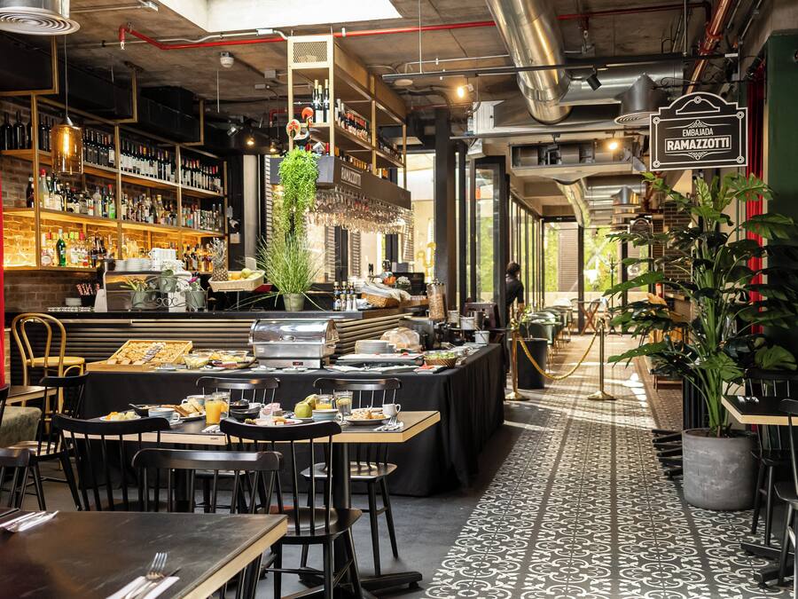 Un restaurante con barra, mesas para comer y un bufé.