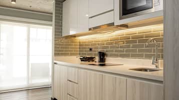 A modern kitchen with a microwave, kettle, and stainless steel sink.