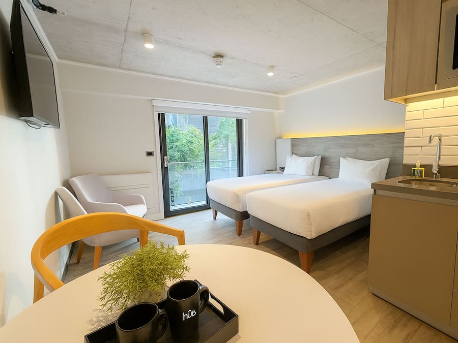 Una habitación de hotel moderna con cama, escritorio, silla, televisor y baño.