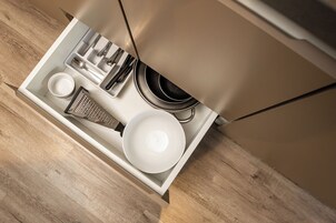 Uma gaveta de cozinha com utensílios, um ralador, uma tigela e um prato.