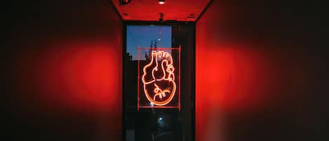 A hallway with a neon sign on a glass door.