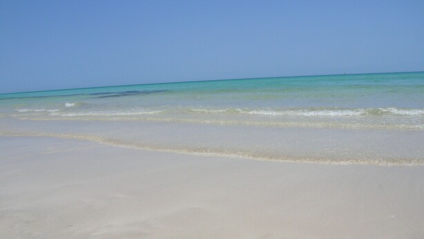 Uma praia com águas azul-turquesa cristalinas e areia branca.