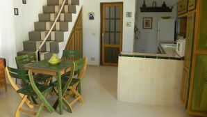 Uma cozinha com painel de azulejos, escada de madeira e área de jantar com mesa e cadeiras.