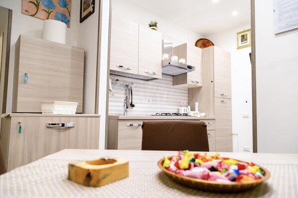 Une cuisine moderne avec des meubles de couleur bois clair, un îlot central et un coin repas avec une table dressée pour deux personnes.