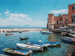 Une ville côtière qui abrite un bâtiment historique, une digue rocheuse et plusieurs bateaux amarrés dans le port.
