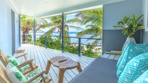Un balcone con pavimento in legno, un divano, sedie e un tavolino.
