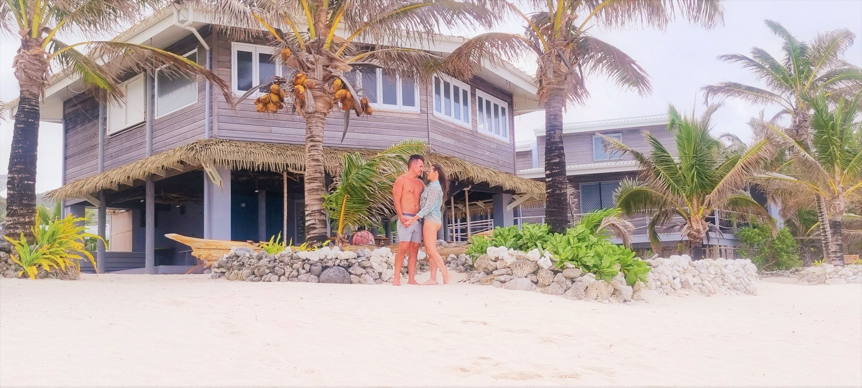 A beachfront property with a thatched-roof structure, palm trees, and a sandy beach.