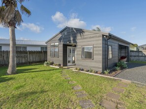 Enjoy a serene atmosphere in this house surrounded by a well-maintained lawn and lush plants.