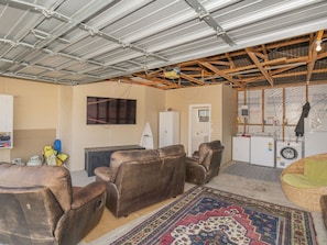 Relax in this spacious room with a high ceiling, featuring a comfortable sofa set, armchair, and wicker chair.