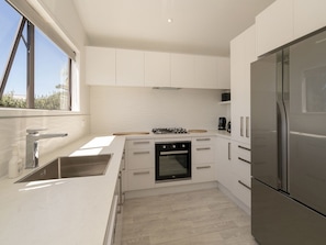 Enjoy cooking in this well-lit kitchen with sleek cabinetry, a refrigerator, and oven.