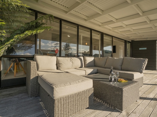 Relax in a stylish outdoor space with a comfortable L-shaped sofa and wicker side tables.