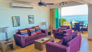 A living room with purple sofas, a coffee table, and a view of the ocean. - Boana Torre Malibu #705 , Two bedrooms, Ocean view & City View, romantic zone (Amapas)