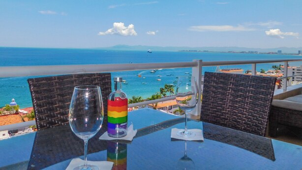 A table with a glass of water and a bottle of Absolut vodka, overlooking a beach with boats and a clear blue sky. - Boana Torre Malibu #705 , Two bedrooms, Ocean view & City View, romantic zone (Amapas)