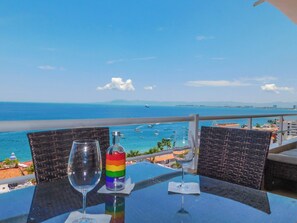 A table with a glass of water and a bottle of Absolut vodka, overlooking a beach with boats and a clear blue sky. - Boana Torre Malibu #705 , Two bedrooms, Ocean view & City View, romantic zone (Amapas)