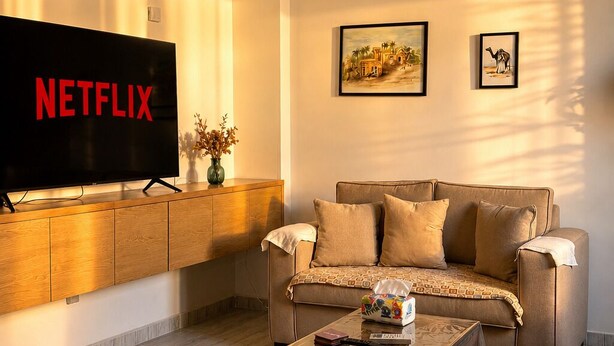 Una sala de estar con una televisión de pantalla plana, un sofá, una mesa de centro y dos lámparas colgantes.