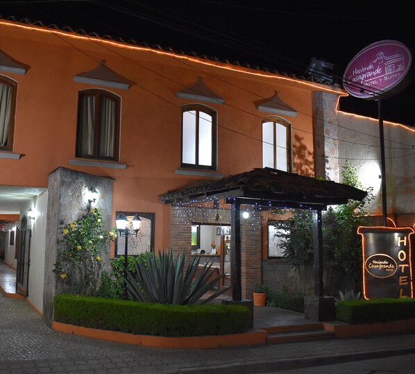 A hotel with a traditional facade, a covered entrance, and a neon sign.