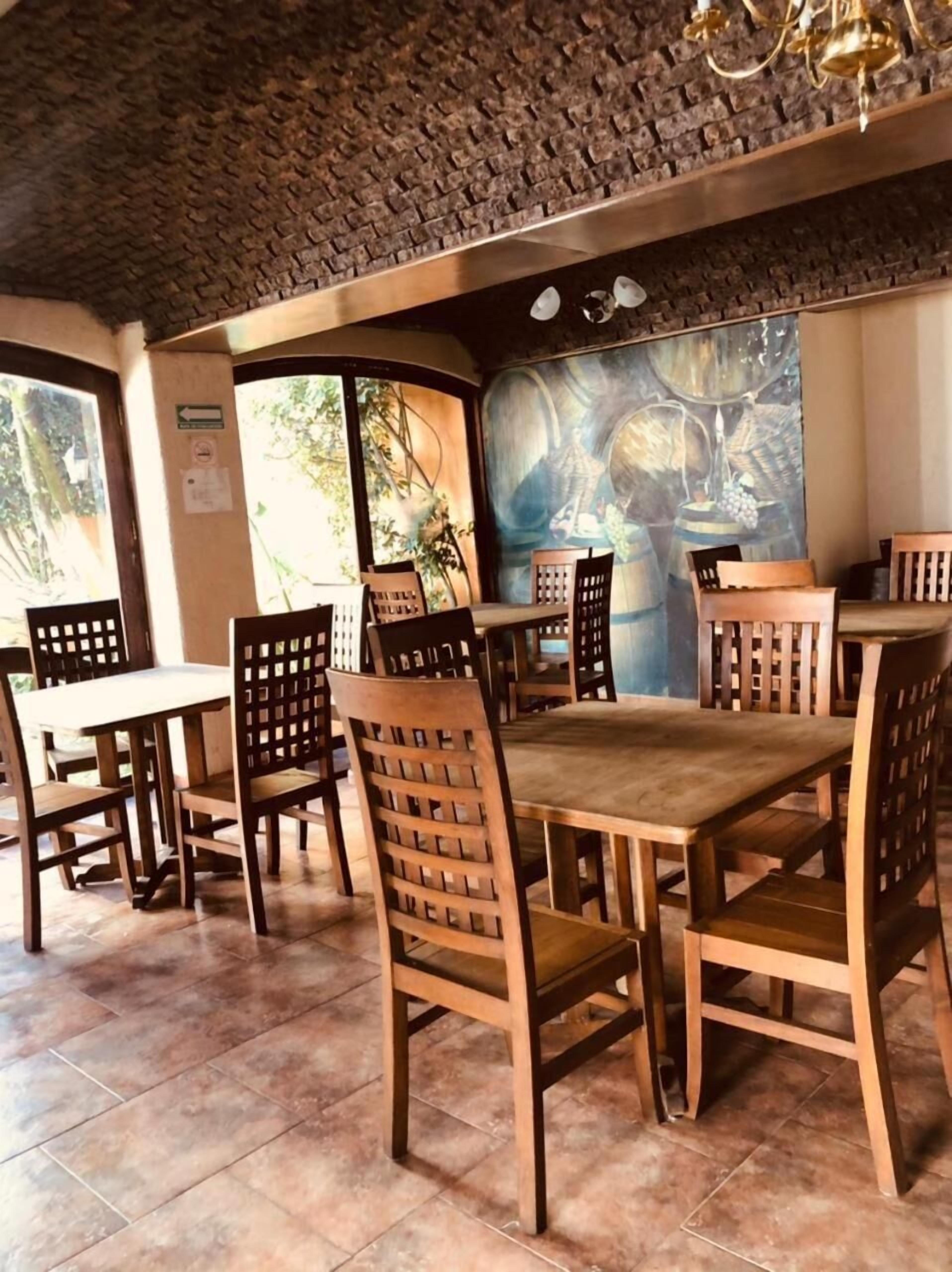 A restaurant interior with wooden tables and chairs, a mural on the wall, and a stone ceiling.