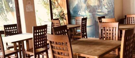 A restaurant interior with wooden tables and chairs, a mural on the wall, and a stone ceiling.