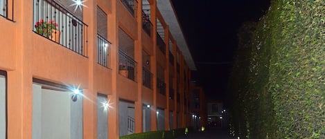 A building with multiple balconies, a cobblestone pathway, and a hedge.