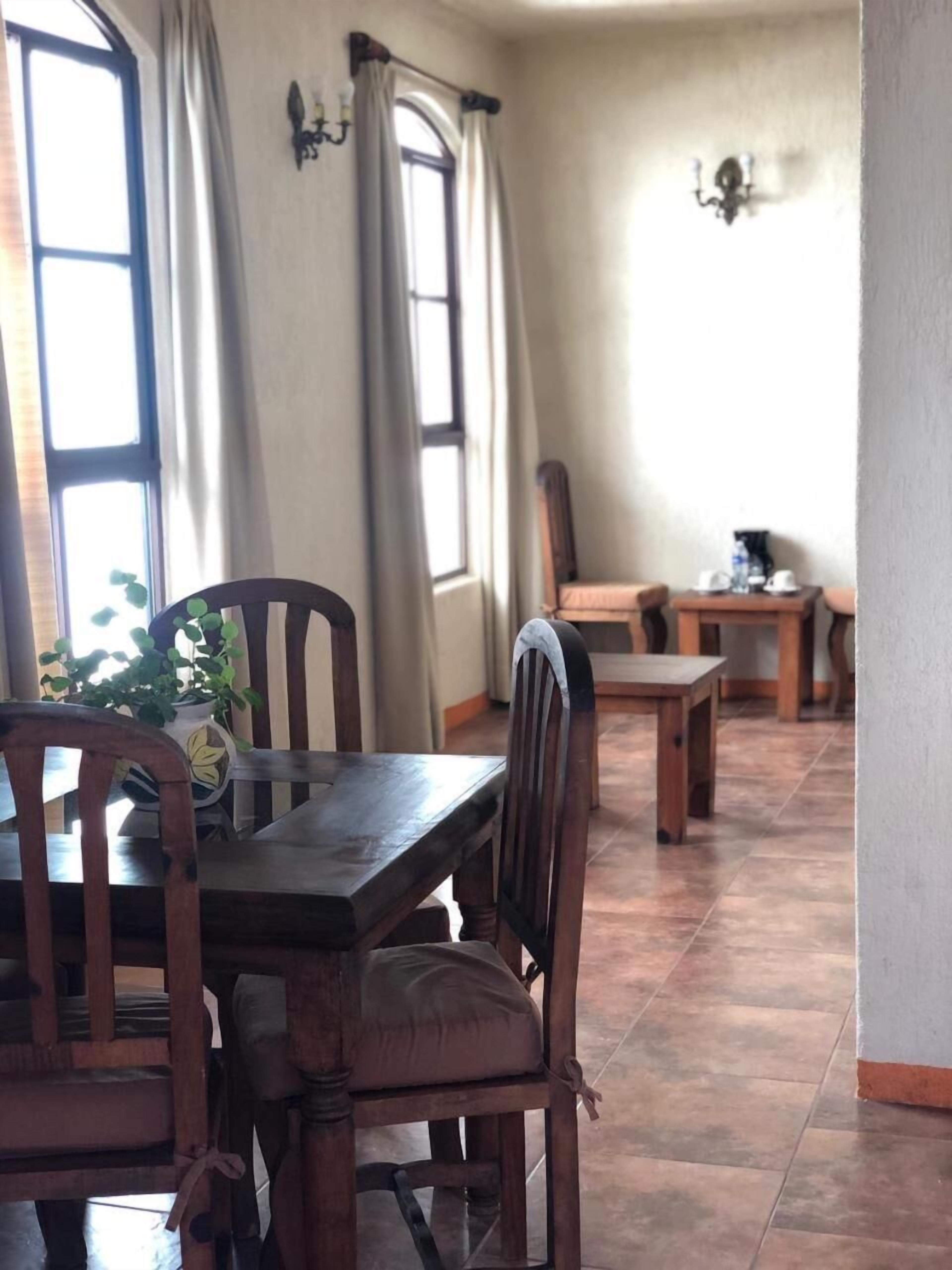 A dining area with wooden furniture, a table, chairs, and a potted plant.