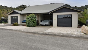 A modern two-story house with a garage, a covered porch, and a driveway. - Blue Lagoon - Kaiteriteri Holiday Unit (Kaiteriteri)