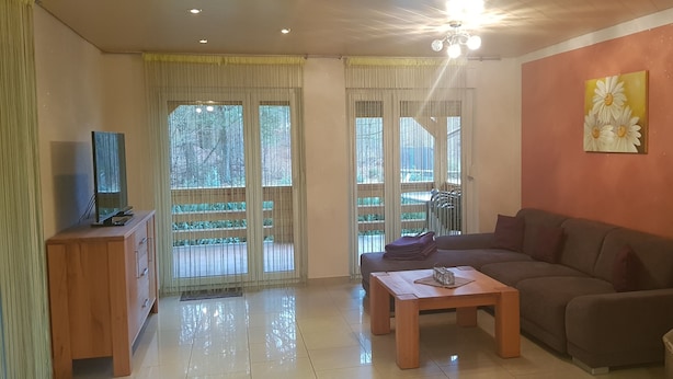 Un salon avec un canapé, une table basse, un téléviseur posé sur un meuble en bois et un tableau accroché au mur.