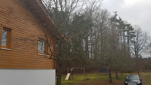 Une maison en bois avec une balançoire et une voiture garée dans l’allée.