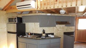 A compact kitchen with grey cabinets, a built-in microwave, and a refrigerator.