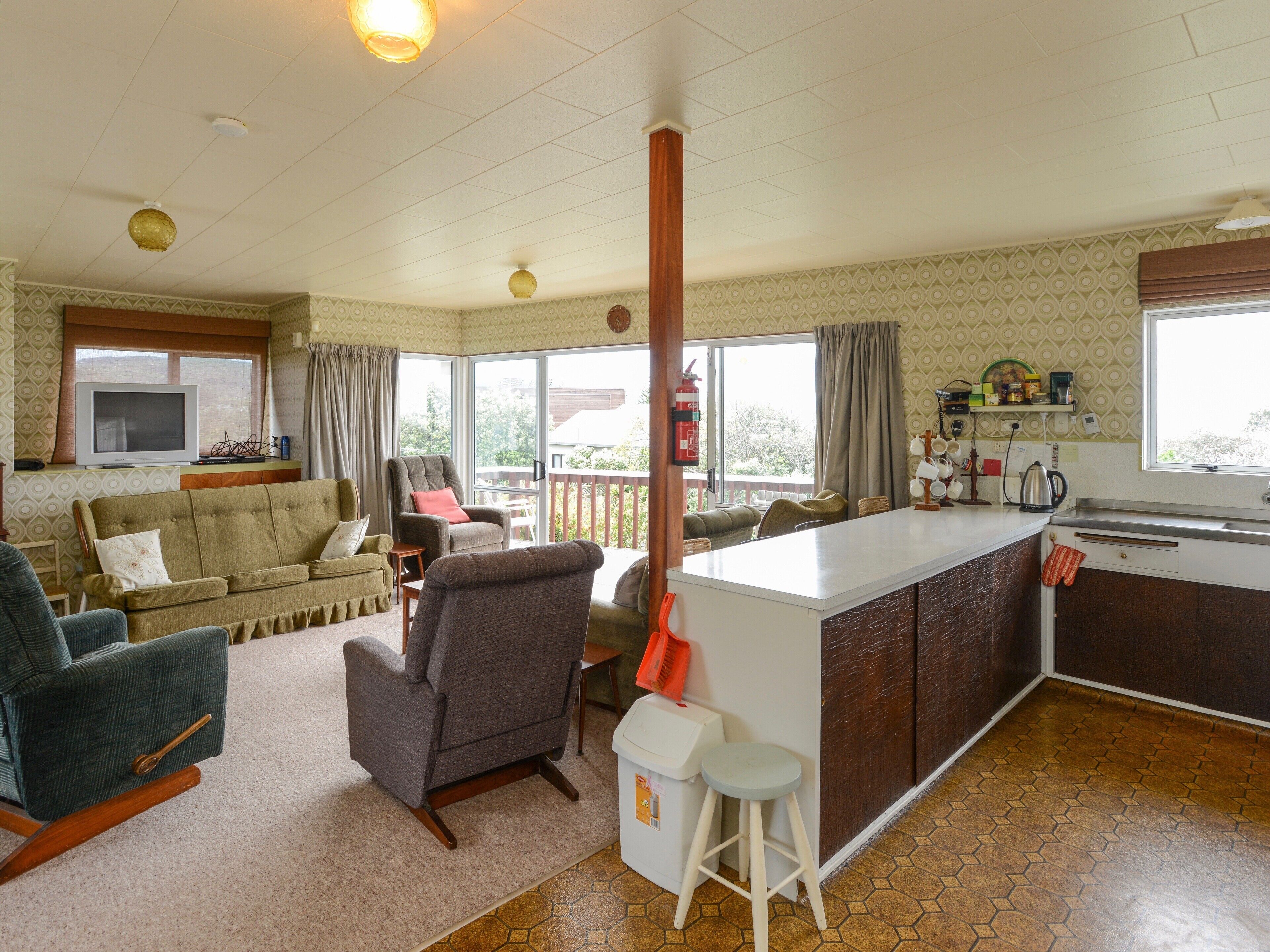 A compact living space with a kitchenette, a sofa, a chair, and a dining area.