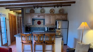 A living room with a wooden coffee table, a black leather sofa, and a colorful rug. - Beautiful Santa Fe downtown property walking distance to the Plaza (Santa Fe)