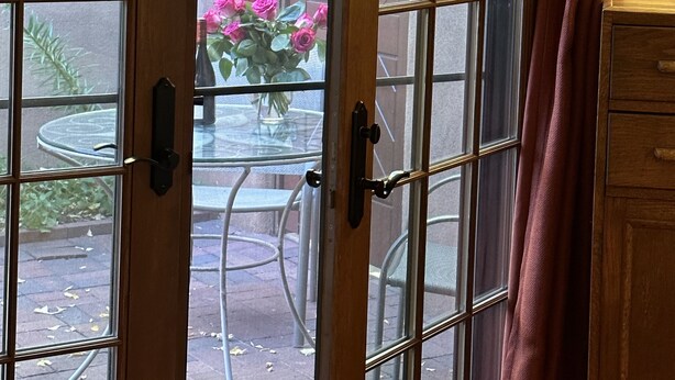 A sliding glass door leading to an outdoor patio with a table and chairs, a small garden, and a wooden cabinet. - Beautiful Santa Fe downtown property walking distance to the Plaza (Santa Fe)