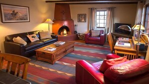 A cozy living room with a fireplace, leather sofas, a wooden coffee table, and a television. - Beautiful Santa Fe downtown property walking distance to the Plaza (Santa Fe)
