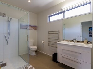Une salle de bain moderne avec une douche à parois de verre, des toilettes, un meuble-lavabo avec un miroir et un porte-serviettes.