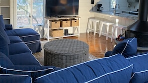 A cozy living room with a large TV, comfortable seating, a kitchen area, and a fireplace. - Middlesex Beach - Sunday to Sunday summer rentals.  Private community beach.  (Bethany Beach)