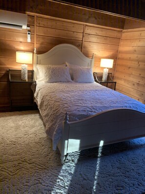 A neatly made bed with a white headboard, two bedside lamps, and a wooden headboard wall. - Middlesex Beach - Sunday to Sunday summer rentals.  Private community beach.  (Bethany Beach)
