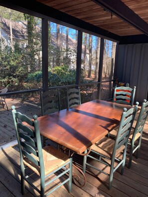 A covered outdoor dining area with a wooden table and chairs, surrounded by a wooden deck and a view of trees and a house. - Middlesex Beach - Sunday to Sunday summer rentals.  Private community beach.  (Bethany Beach)