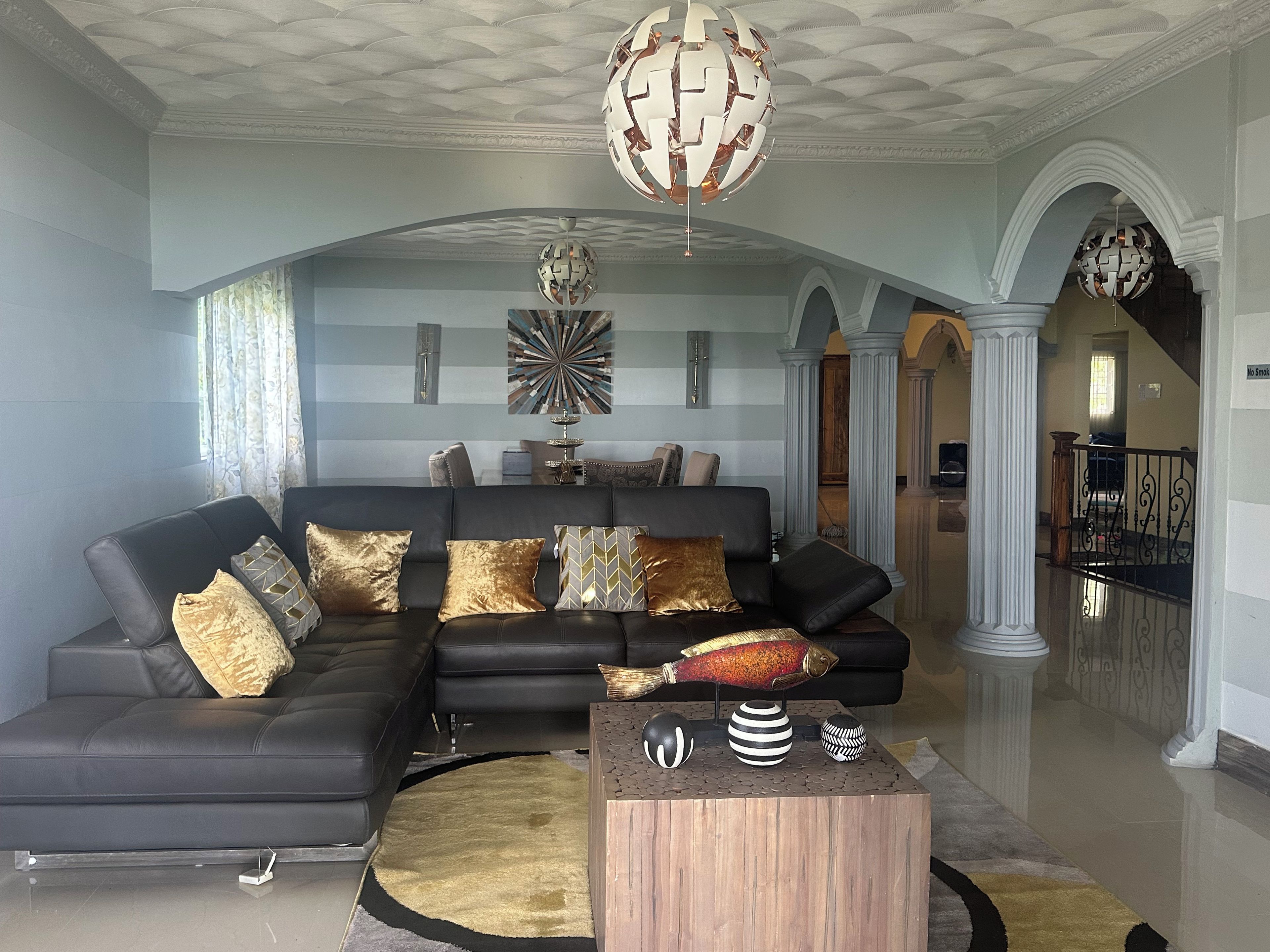 A modern living room with a sectional sofa, decorative pillows, a unique fish sculpture, and a contemporary chandelier.