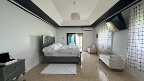 A modern bedroom with a bed, a chair, a dresser, and a view of the outdoors. - Luxury ocean view villa  (Westmoreland)