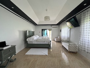 A modern bedroom with a bed, a chair, a dresser, and a view of the outdoors. - Luxury ocean view villa  (Westmoreland)