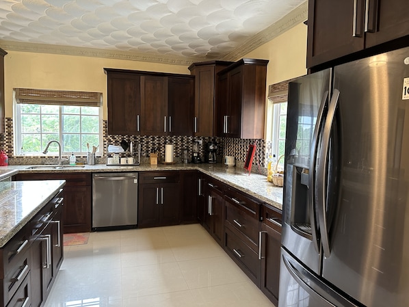 A modern kitchen with dark wood cabinets, stainless steel appliances, and a checkered backsplash. - Luxury ocean view villa (Westmoreland)