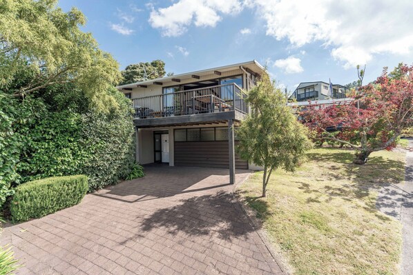 Une maison à deux étages avec une allée couverte, un balcon et un garage.